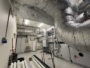 Photo réaliste d’un local technique avec unité de ventilation double flux et gaines isolées